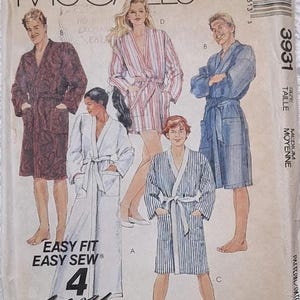 May include: A McCall's 3931 sewing pattern envelope for medium-sized robes. The front features illustrations of four different robe styles, including solid, striped, and patterned designs, with the text Easy Fit Easy Sew 4 Pieces.