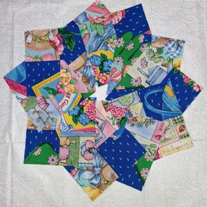 May include: A star-shaped quilt block composed of various fabric squares. The squares feature floral, garden, and polka dot patterns in shades of blue, pink, green, and yellow. The design is arranged on a white background.