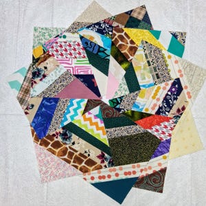 May include: A star-shaped quilt block constructed from numerous fabric strips in a variety of colors and patterns, including floral, geometric, chevron, plaid, and animal print designs, arranged in a radiating pattern from the center outward.