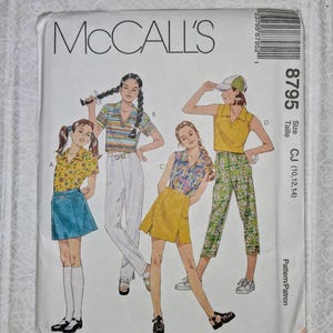 May include: A vintage McCall's sewing pattern envelope featuring illustrations of four young women in various outfits. The pattern number is 8795, with size CJ (10,12,14). The envelope is white with black text and a barcode.
