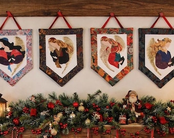 May include: Four fabric wall hangings with pointed bottoms, each featuring a central illustration of an angel with gold wings. The banners are suspended by red ribbons and display distinct patterned borders in floral, paisley, and dark geometric prints.