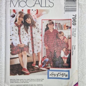 May include: A McCall's sewing pattern featuring children's sleepwear. The pattern includes images of children wearing red plaid and white patterned pajamas. The pattern is size extra small.