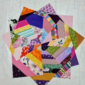 May include: A star-shaped quilt block composed of numerous fabric strips in a variety of colors and patterns, including floral, polka dot, heart, and geometric prints. The design features a central point with radiating sections of fabric.
