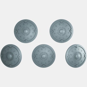 May include: Five silver-coloured round shields with runes and a circular design in the centre. The shields are arranged in a circle with one shield at the top, two on the sides, and two at the bottom.