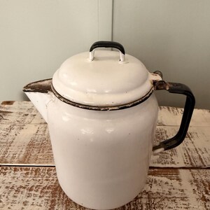 May include: A white ceramic mug with a black handle and the text "But First, Coffee" in a black, bold font. The mug is on a white surface. The mug is approximately 4 inches tall.