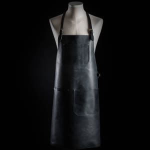May include: A black leather apron with adjustable straps and multiple pockets. The apron is made of high-quality leather and is designed for durability and functionality.