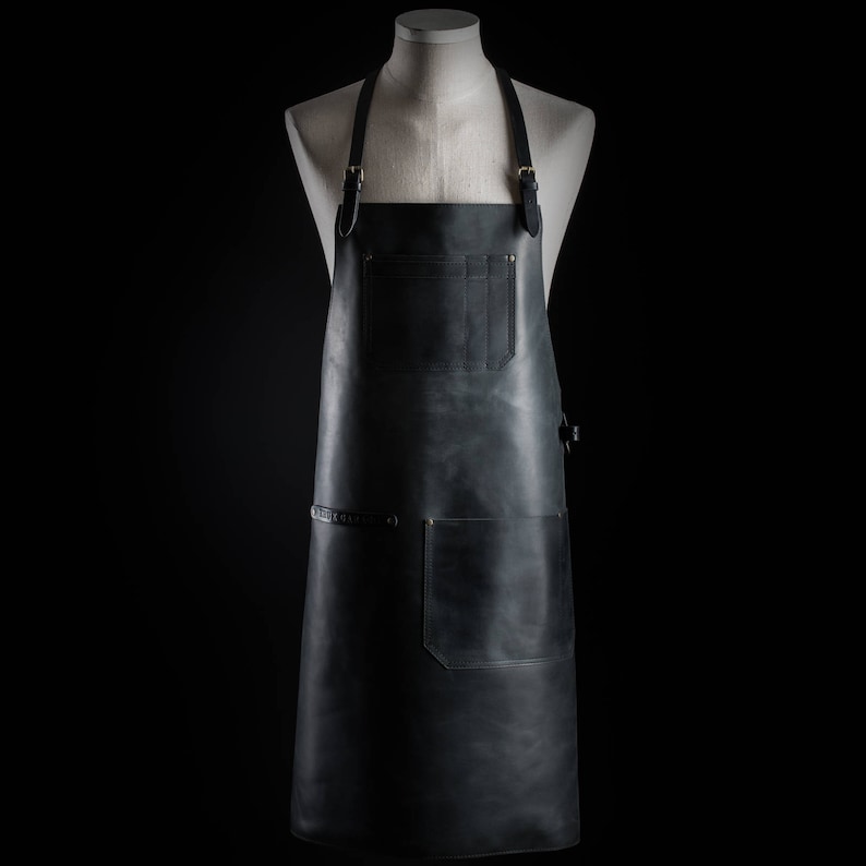 May include: A black leather apron with adjustable straps and multiple pockets. The apron is made of high-quality leather and is designed for durability and functionality.