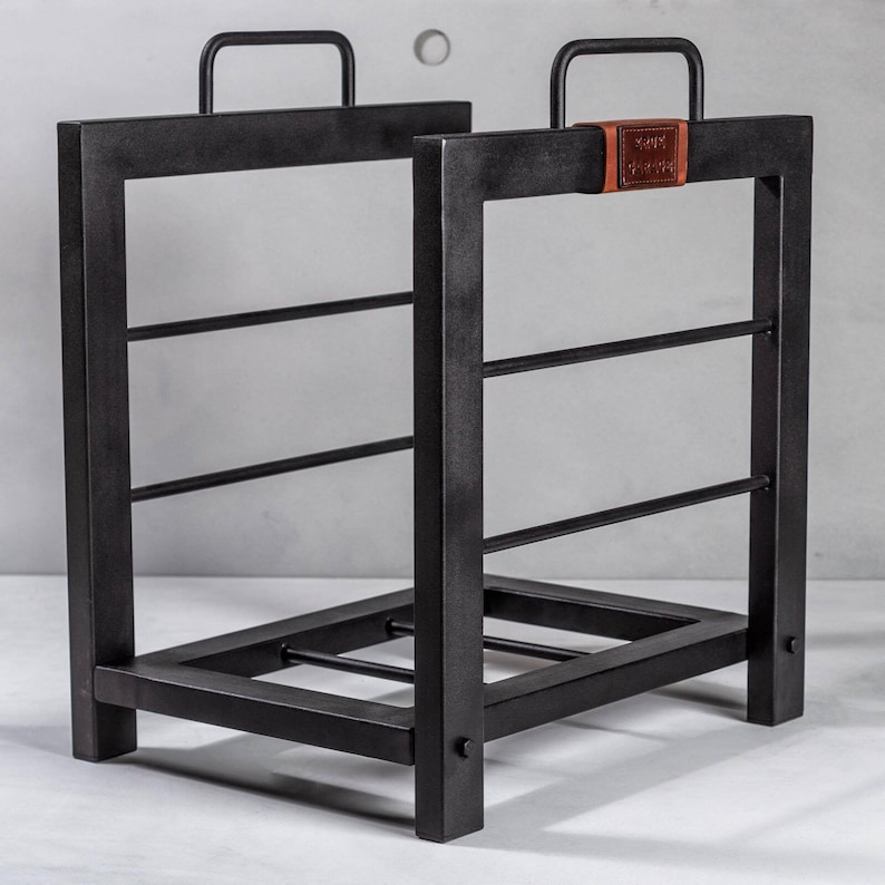 May include: Black metal log rack with three shelves and a leather strap with the text "Keep Calm and Carry On".