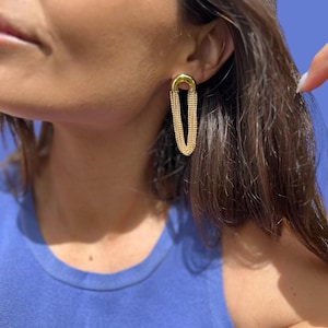 May include: Gold chain earrings with a long, dangling design. The earrings are made of multiple chains connected together.