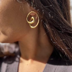May include: Gold-toned hoop earrings with a twisted design. The earrings are made of metal and have a polished finish.