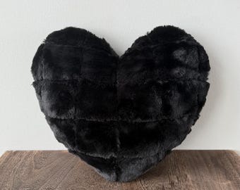 May include: A black heart-shaped pillow with a quilted design. The pillow is made of soft, plush fabric.