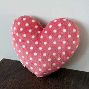 May include: A pink heart-shaped pillow with white polka dots.