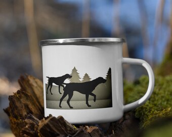 Könnte beinhalten: Weiße Email Tasse mit einer schwarzen Silhouette von zwei Deutsch Kurzhaar in einer Waldlandschaft. Die Tasse hat einen silbernen Rand und einen Henkel.