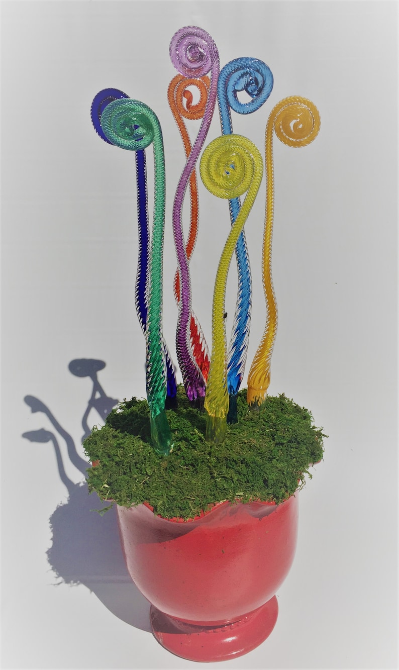 May include: A rainbow-colored glass sculpture of fern-like plants in a red pot with green moss. The sculpture is made of glass and is a unique and colorful piece of art.