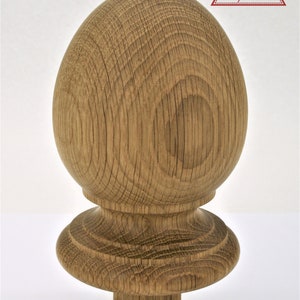 May include: A wooden finial with a rounded top and a base with a decorative edge. The finial is made of natural wood with a light brown colour and a visible grain pattern.
