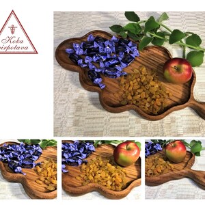 May include: A wooden serving tray shaped like a leaf with a handle. The tray is filled with purple candies, yellow raisins, and a red apple.