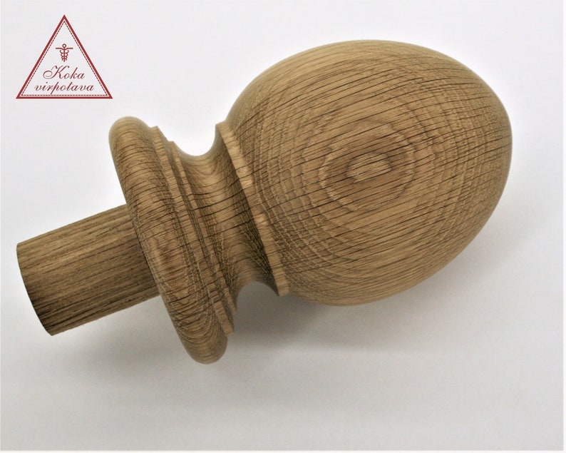 May include: A wooden finial with a rounded top and a fluted base. The finial is made of light brown wood with a natural finish.