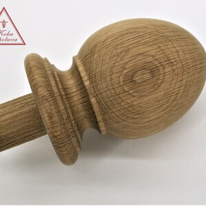 May include: A wooden finial with a rounded top and a fluted base. The finial is made of light brown wood with a natural finish.