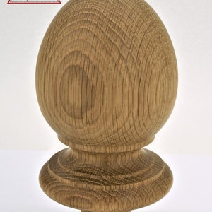 May include: A wooden finial with a rounded top and a base with a decorative ring. The finial is made of light brown wood with a natural grain pattern.