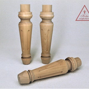 May include: Three wooden table legs with a turned design. The legs are made of light-colored wood and have a smooth finish.