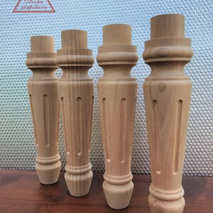 May include: Four wooden table legs with a fluted design. The legs are unfinished and have a natural wood color.