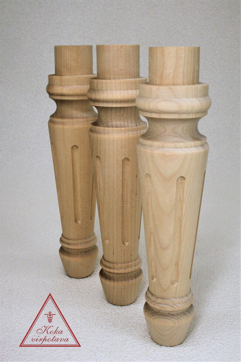 May include: Three unfinished wooden table legs with a turned design and a fluted detail. The legs are made of light-colored wood and have a smooth finish.