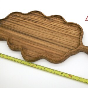 May include: A large, wooden serving tray shaped like a leaf with a handle. The tray is made of dark brown wood with a natural grain pattern. The tray is approximately 17 inches long.