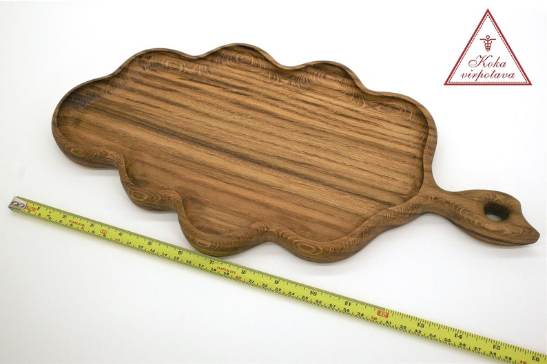 May include: A large, wooden serving tray shaped like a leaf with a handle. The tray is made of dark brown wood with a natural grain pattern. The tray is approximately 17 inches long.