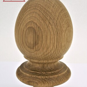 May include: A wooden finial with a rounded top and a base with a decorative ring. The finial is made of light brown wood with a natural finish.