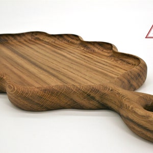 May include: A large, wooden serving tray shaped like a leaf with a handle. The tray is made of dark wood with a natural grain pattern. The handle has a hole in it for easy carrying.