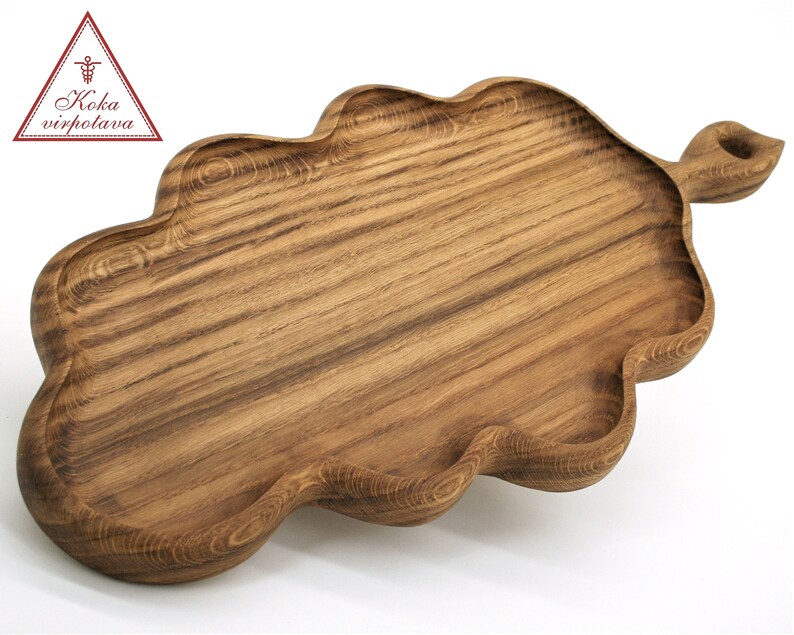 May include: A wooden serving tray shaped like an oak leaf with a handle. The tray is made of dark brown wood with a natural grain pattern.
