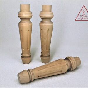 May include: Three wooden table legs with a turned design. The legs are made of light-colored wood and have a smooth finish.