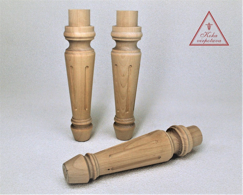 May include: Three wooden table legs with a turned design. The legs are made of light brown wood and have a smooth finish.