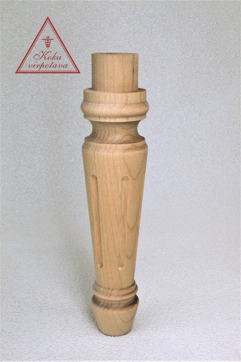 May include: A wooden furniture leg with a turned design and a rounded bottom. The leg is light brown in color and has a smooth finish.