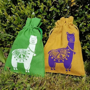 May include: Two small drawstring bags with llama designs. The bag on the left is green with a white llama. The bag on the right is yellow with a purple llama.