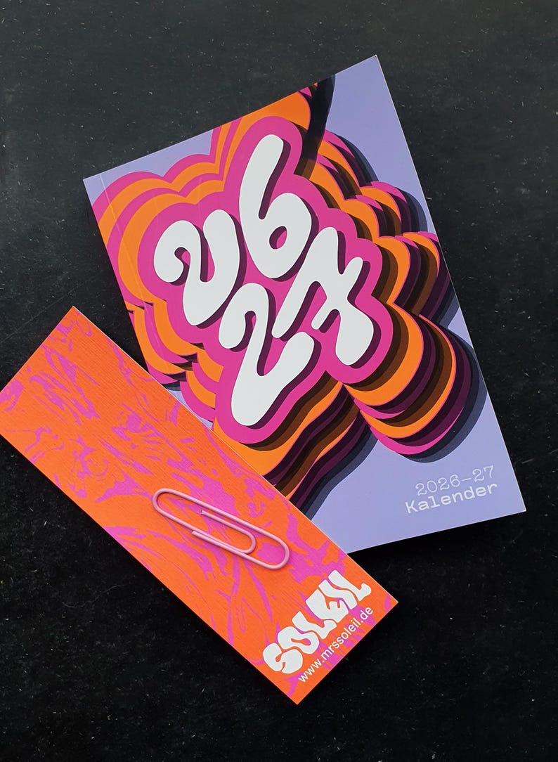 May include: A calendar and a card with a pink paperclip. The calendar has a purple background with the numbers "26 27" in white, and the word "Kalender" in the corner. The card is orange with pink swirls and the word "SOLEIL" in white.