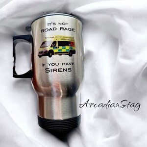 May include: A stainless steel travel mug with a black handle and lid. The mug has a graphic of an ambulance with the text "It's not road rage if you have sirens".