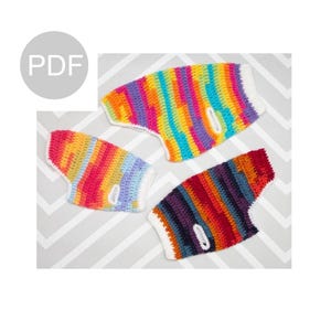 Puede incluir: Tres jerséis de crochet para perros de colores arcoíris. Los jerséis son de rayas y tienen un ribete blanco. Los jerséis están dispuestos sobre un fondo de patrón de chevron gris y blanco.