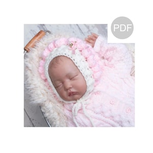 May include: A pink and white crocheted baby bonnet with a flower embellishment. The bonnet has a ruffled edge and a tie at the back.