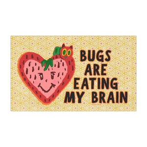 May include: A rectangular print featuring a yellow background with a white floral pattern. On the left, a red heart-shaped strawberry with a smiling face and a green caterpillar on top. To the right, the black text reads BUGS ARE EATING MY BRAIN.