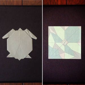 May include: Two origami figures on a black background. The figure on the left is a grey origami turtle. The figure on the right is a green, blue and white origami flower.