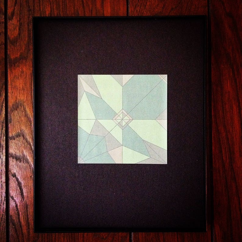 May include: A framed geometric art print with a green, blue, and white colour scheme. The print features a symmetrical design with a diamond shape in the centre.