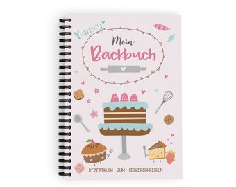 May include: A pink spiral bound notebook with the title "Mein Backbuch" (My Baking Book) in a brown circle with a white heart. The cover features a cartoon cake with strawberries, a rolling pin, a whisk, and other baking-themed illustrations. The text "Rezeptbuch - zum - Selberschreiben" (Recipe Book - for - Writing Yourself) is at the bottom.