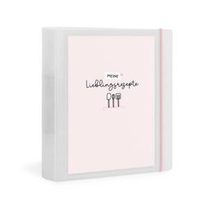 Könnte beinhalten: Ein klarer, weißer Ordner mit rosa Deckblatt, auf dem der Text "MEINE Lieblingsrezepte" und Illustrationen von Küchenutensilien abgebildet sind. Ein rosa Gummiband sichert den Ordner. Ideal zum Organisieren von Rezepten.