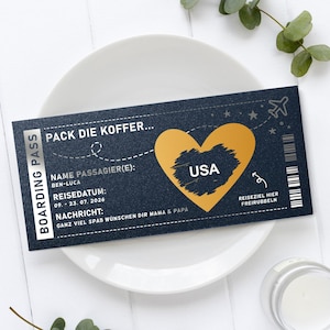 Könnte beinhalten: Eine marineblaue Bordkarte mit goldenen Akzenten, die den Text "PACK DIE KOFFER..." und "USA" in einem Herz zeigt. Der Pass enthält Details wie "BEN-LUCA" und ein Reisedatum. Das Design liegt auf einem weißen Teller.