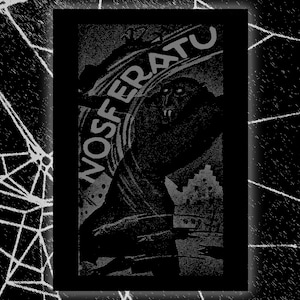 May include: Black and white graphic art print featuring the word "NOSFERATU" above a shadowy figure with sharp teeth. The image has a vintage, horror movie aesthetic, with a spiderweb design in the background.