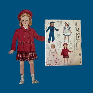 May include: A paper doll wearing a red beret, a double-breasted red coat, and a red plaid skirt, accompanied by a McCall printed pattern envelope for doll outfits, featuring illustrations of various garments and the text McCall Printed Pattern.