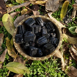 A tribal marked bowl sitting in a patch of grass full of defined black mineral stone rods.