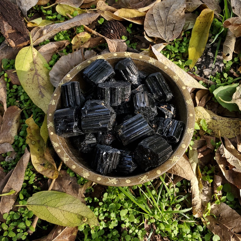 A tribal marked bowl sitting in a patch of grass full of defined black mineral stone rods.