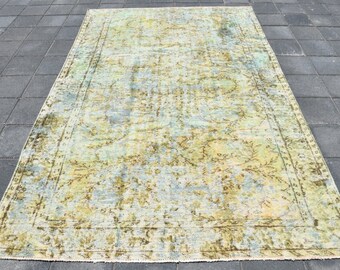 以下が含まれることがあります： 緑、青、黄色の色合いの、色あせた花柄のヴィンテージラグ。ラグは使い古したような外観で、縁がすり切れている。